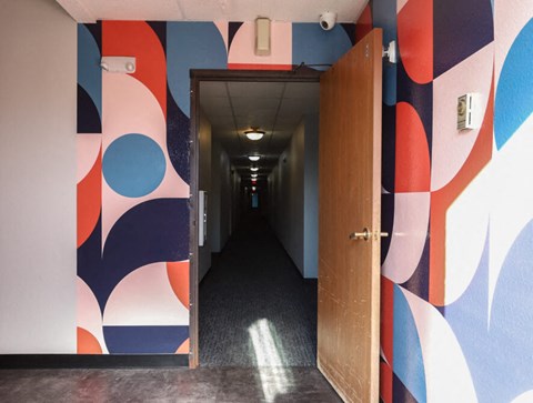 a hallway with a door and a colorful wall with geometric shapes