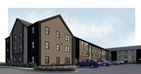 A modern apartment complex with a parking lot in front.