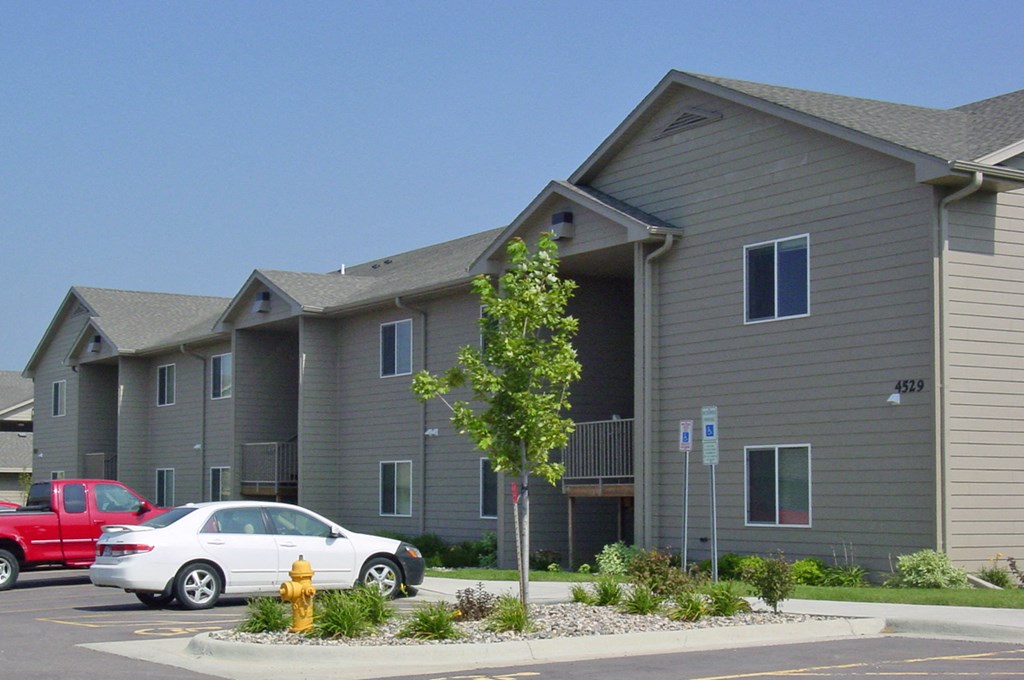a gray apartment building with cars parked in front of it