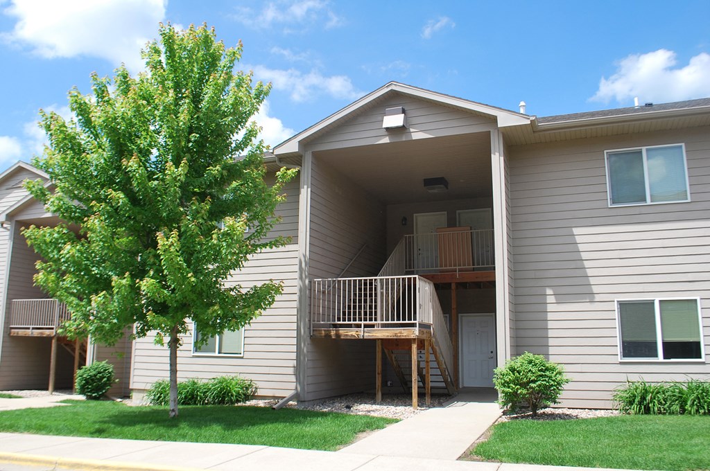 an exterior view of an apartment building with a tree in the yard