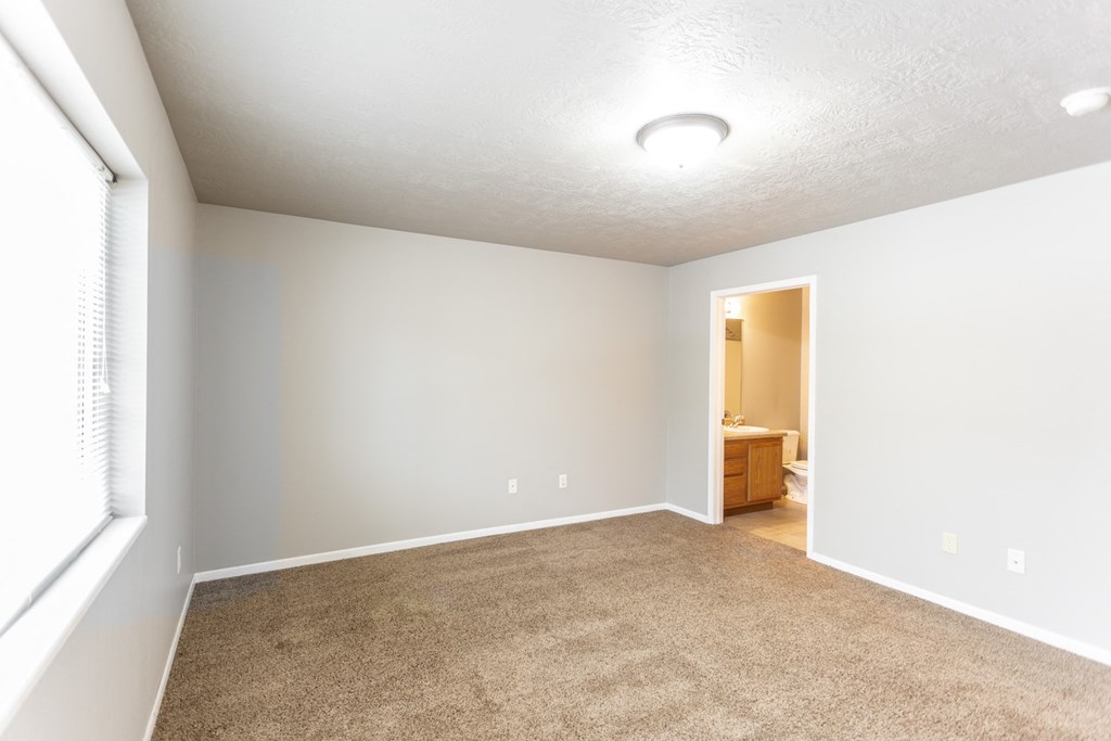 an empty living room with carpet and a large window