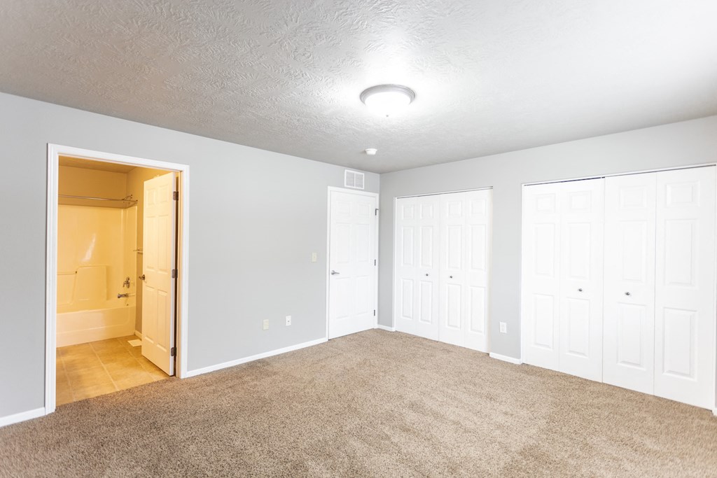 an empty living room with white closets and carpet