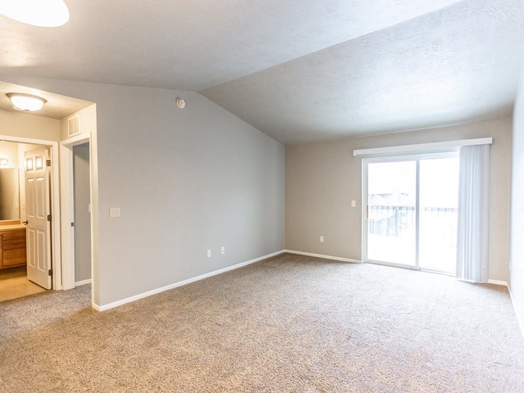 an empty living room with a door to a balcony