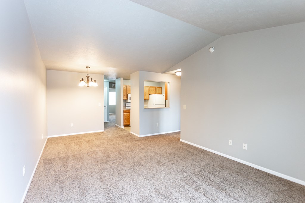a spacious living room with carpet and a view of the kitchen