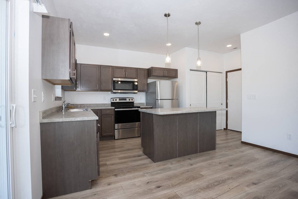 an empty kitchen with wooden floors and stainless steel appliances