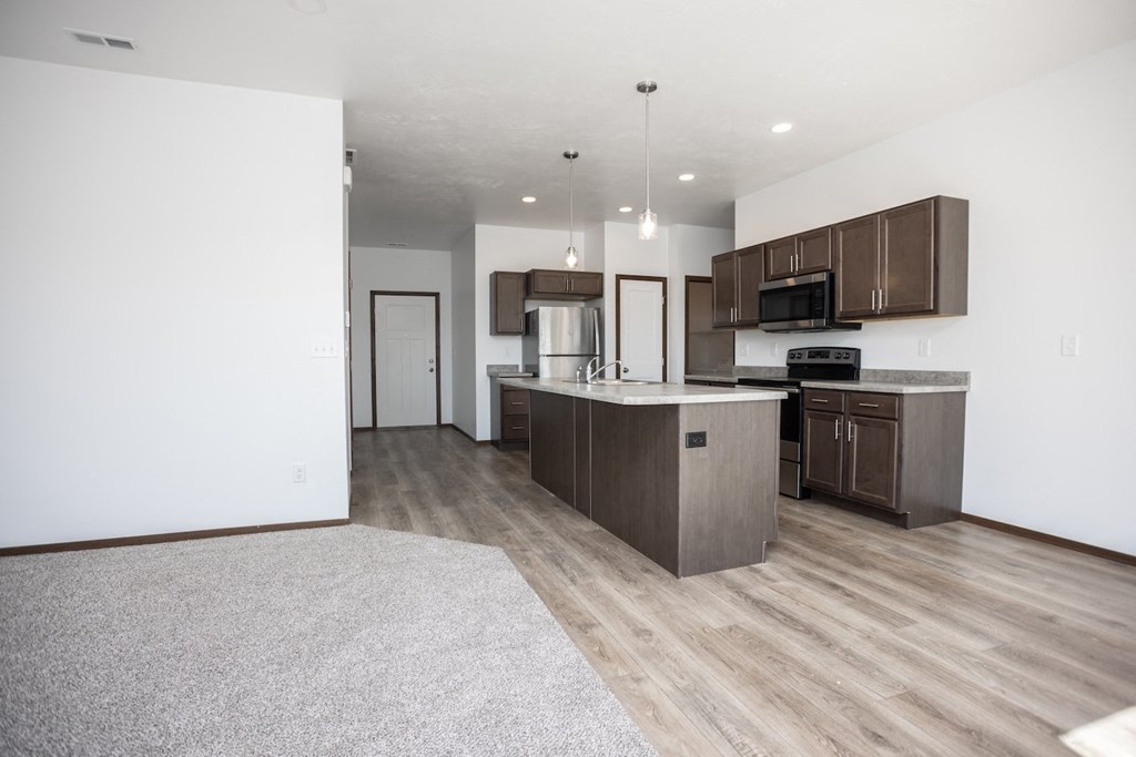 an open kitchen and living room with wood flooring and