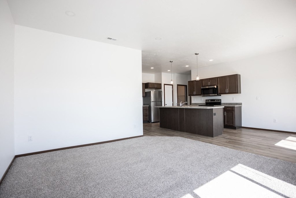an empty living room and kitchen with white walls and wood floors