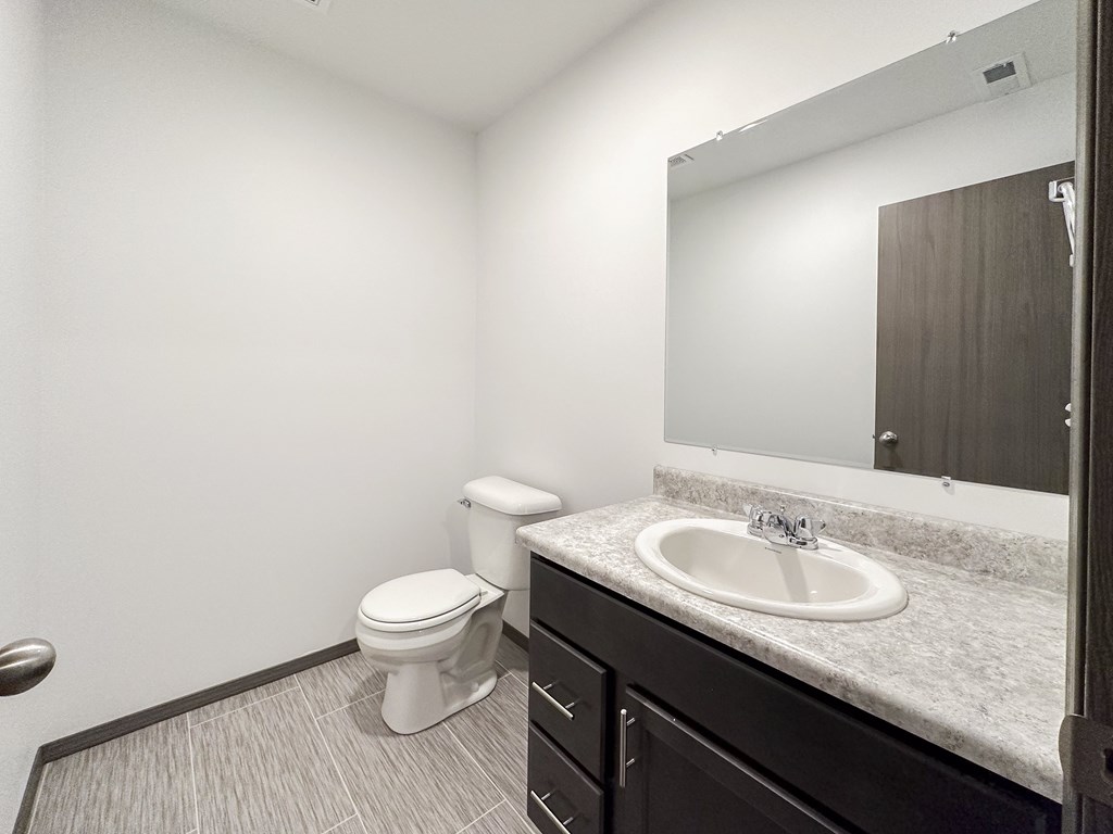 A bathroom with a toilet, sink, and mirror.