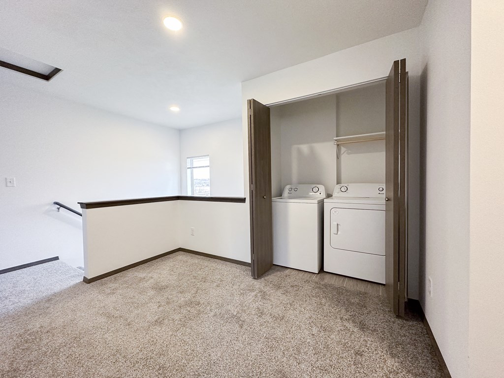 a laundry room with a washer and dryer and white walls and carpeting