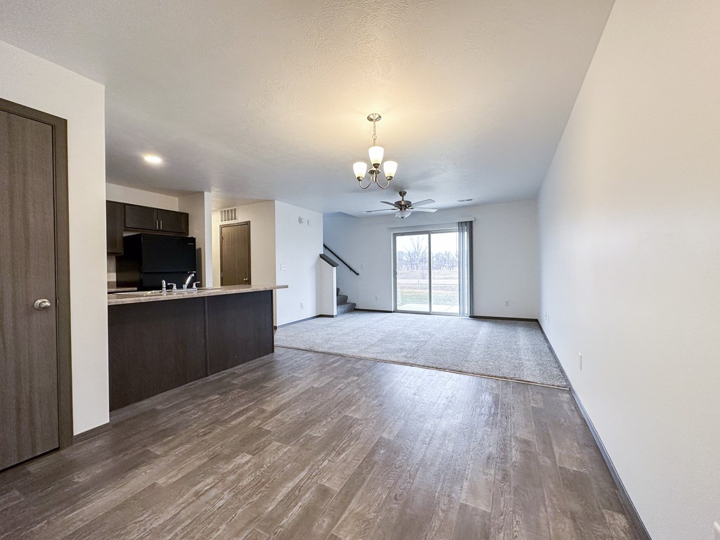 A spacious living room with wood flooring and a ceiling fan.