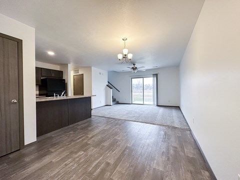 A spacious living room with wood flooring and a ceiling fan.