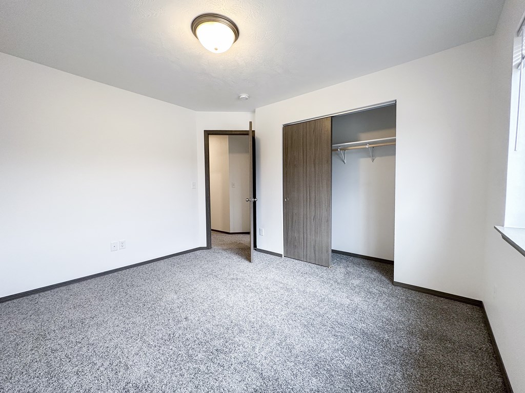 A room with a grey carpet and a wooden door.