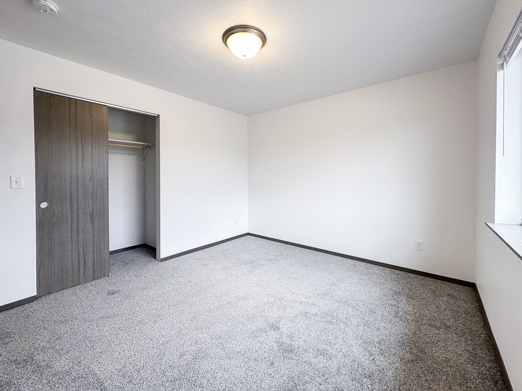 A room with a carpeted floor and a door leading to another room.
