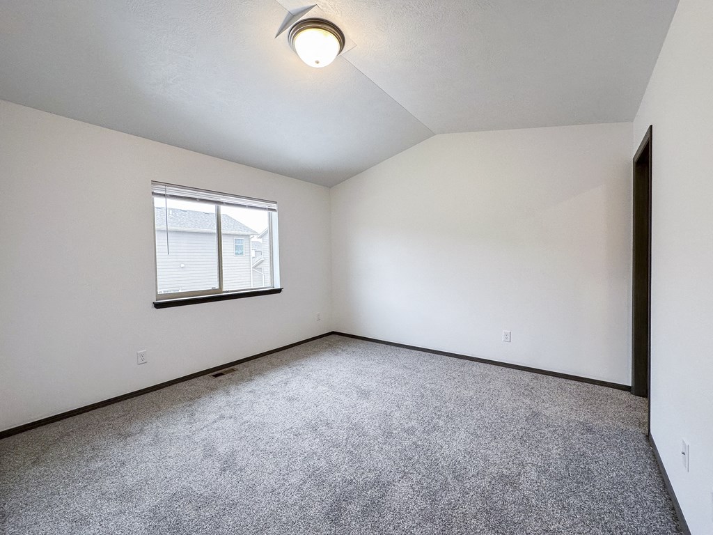 the living room of an empty home with carpet and a window