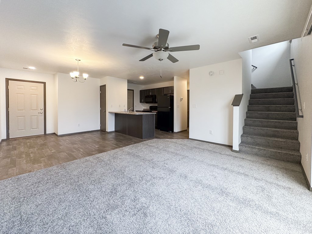 A spacious living room with a staircase on the right side.
