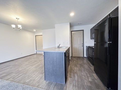 A kitchen with a black refrigerator and a wooden island.