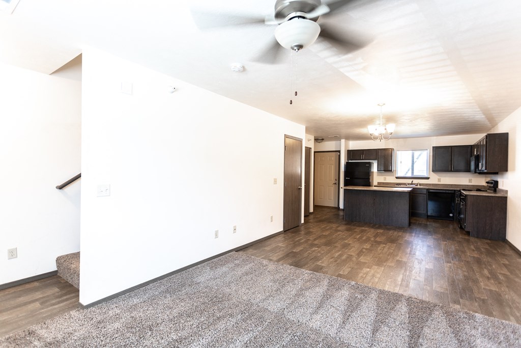 an empty living room and kitchen with a ceiling fan