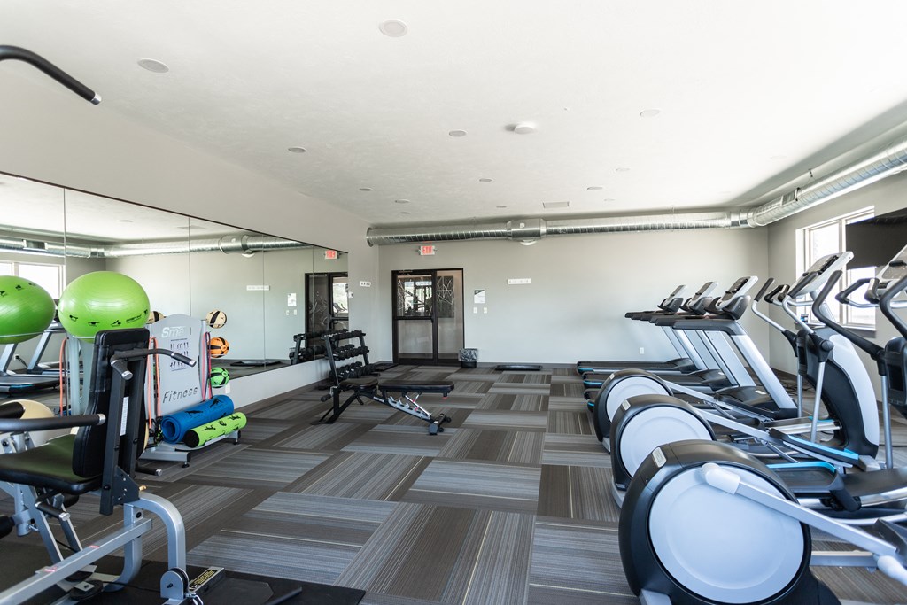 a gym with cardio machines and weights on a tiled floor