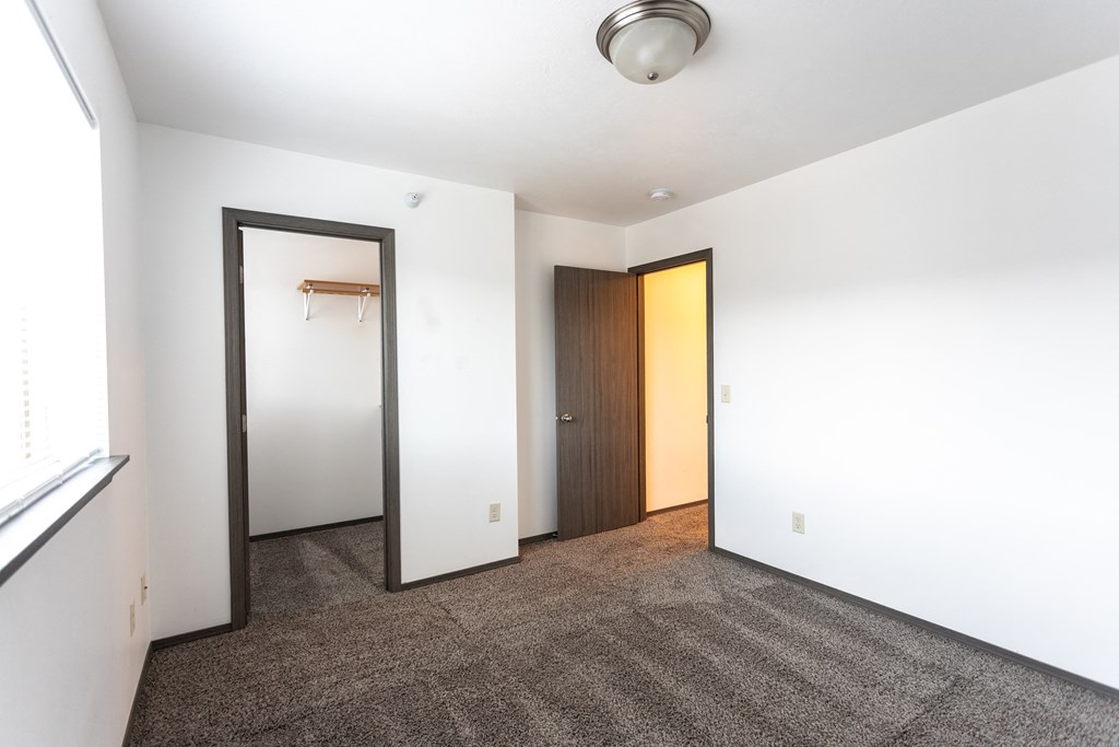 an empty room with a door to a closet and a mirror