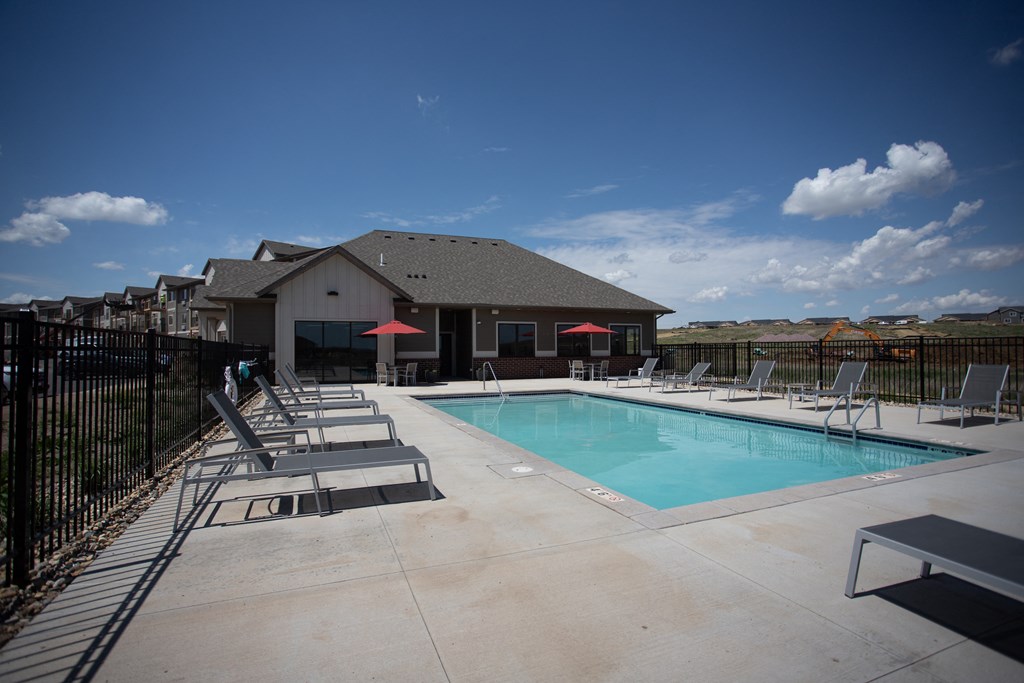 a pool with lounge chairs and a building with a roof