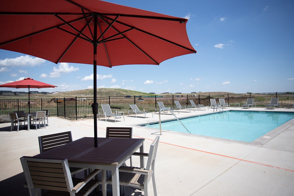 a pool with a table and chairs and a red umbrella
