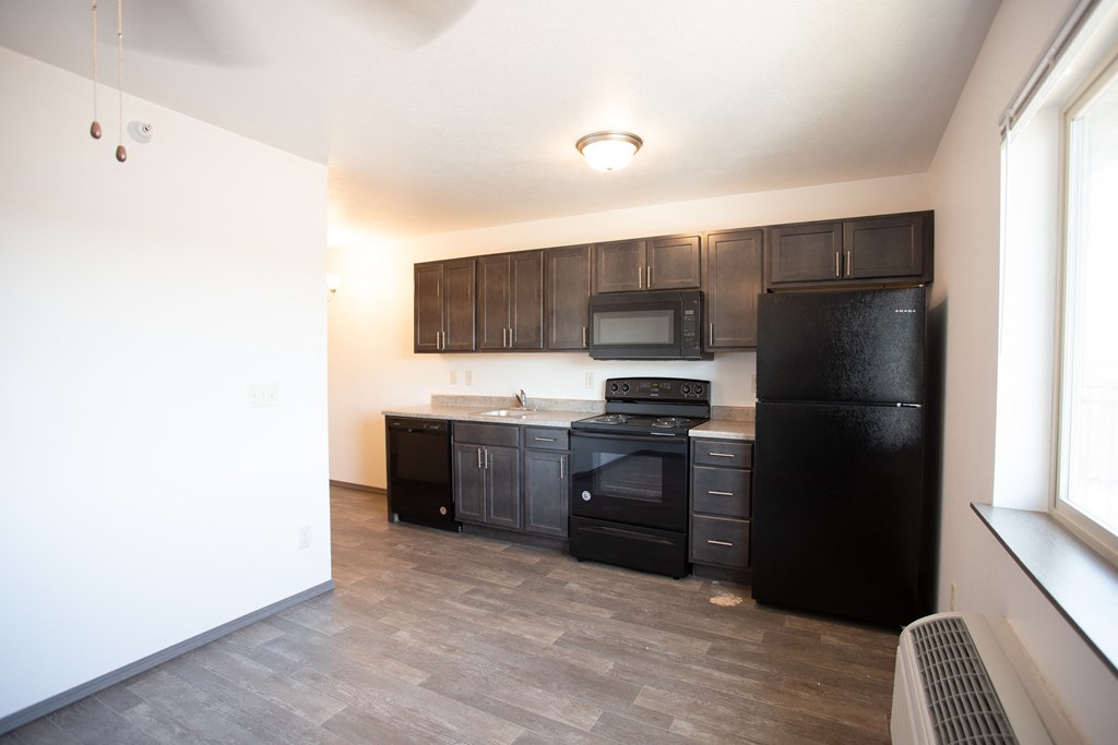 an empty kitchen with black appliances and wooden cabinets