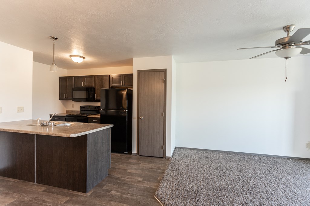 an empty apartment with a kitchen and a ceiling fan