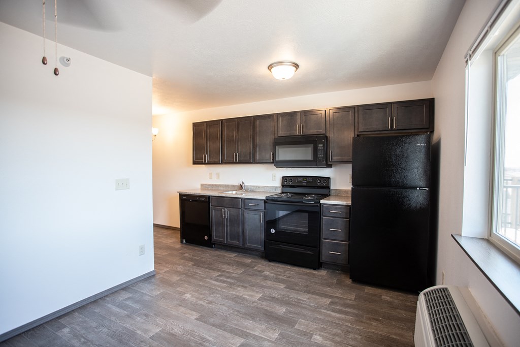 an empty kitchen with black appliances and dark wood cabinets