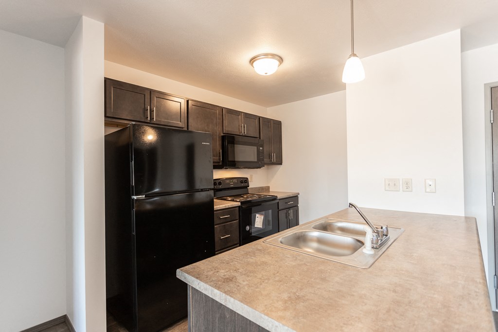 an empty kitchen with a sink and a black refrigerator
