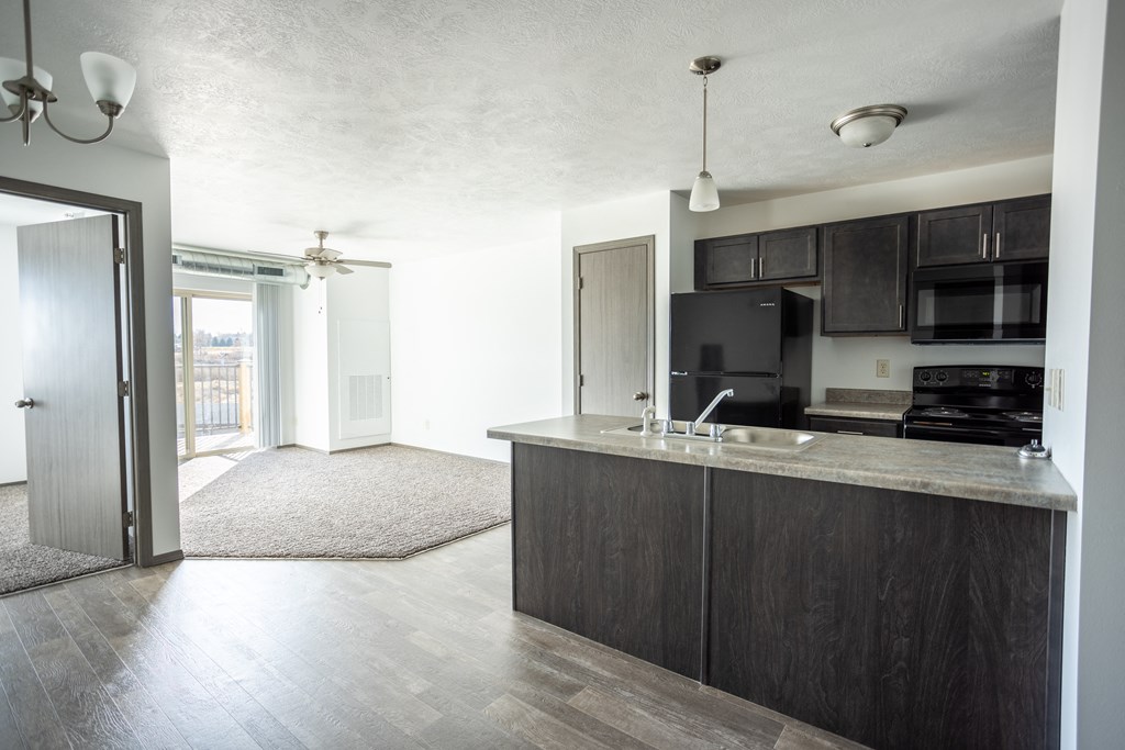 an open kitchen and living room with a sliding glass door to a balcony