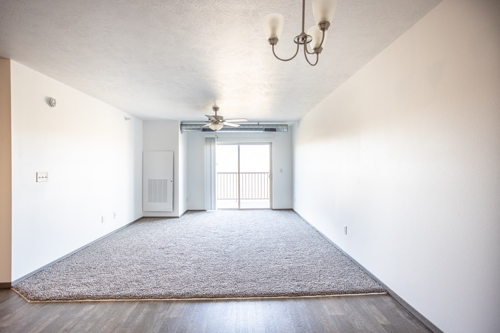 an empty living room with a rug and a ceiling fan