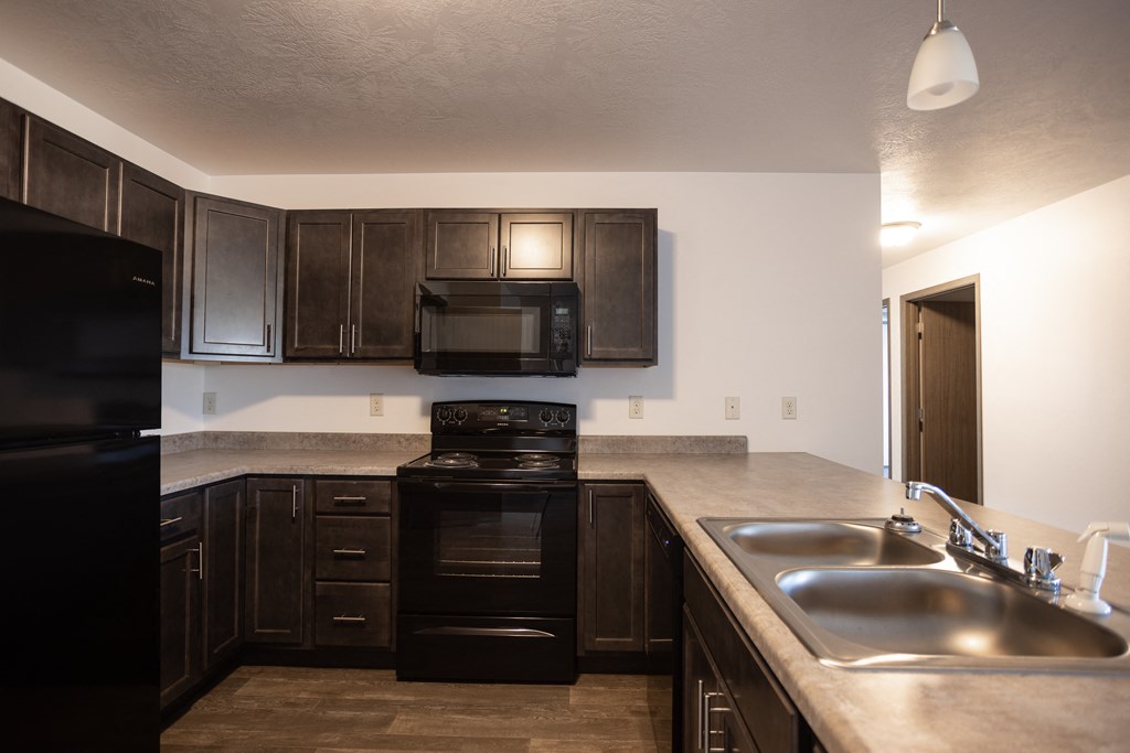 an empty kitchen with dark wood cabinets and a stainless steel sink