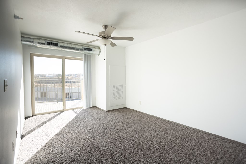 an empty living room with carpet and a ceiling fan