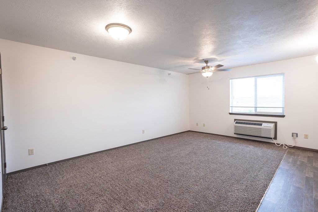 an empty living room with a ceiling fan and a window