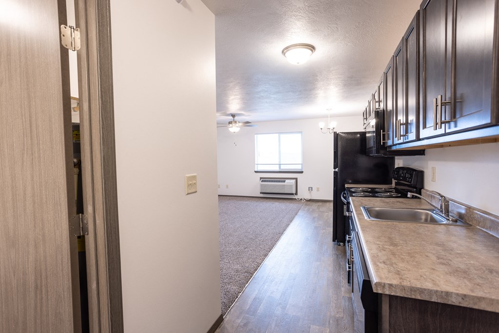an open kitchen and living room of an apartment with black appliances and white walls