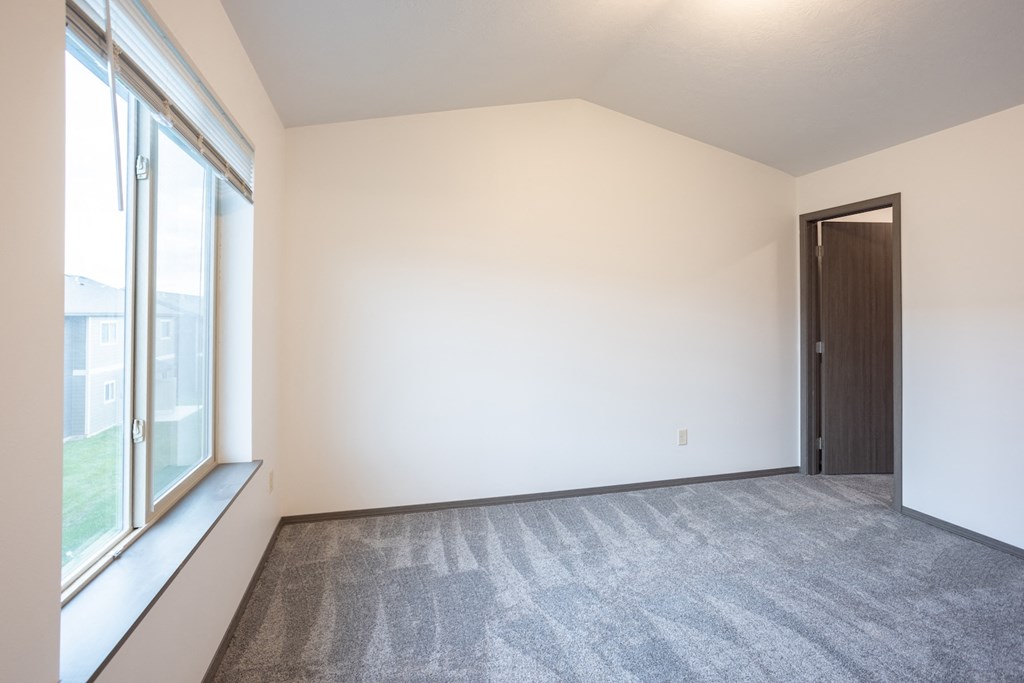 an empty living room with a large window and carpet