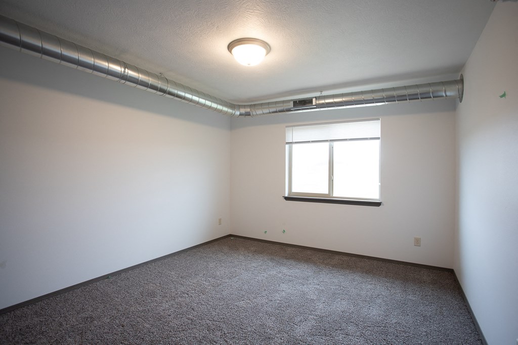 an empty room with a window and carpeting