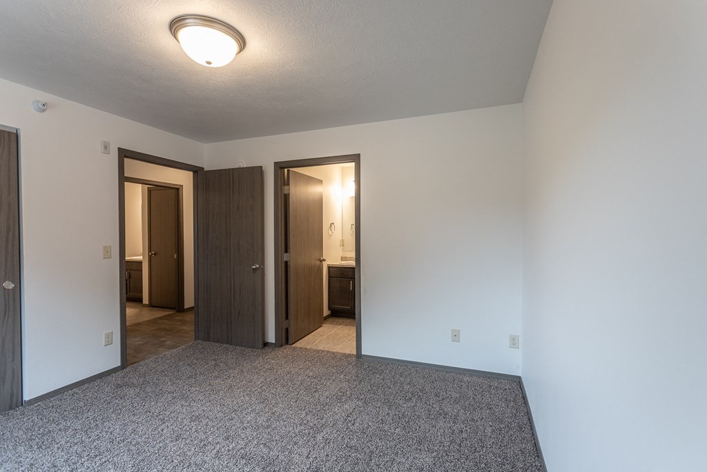 an empty living room with a carpet floor and a door to a bathroom and a