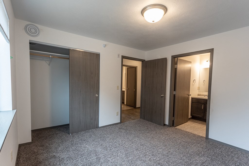 an empty living room with three doors and a bathroom