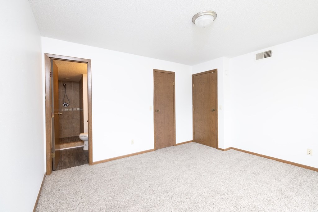 A room with a carpeted floor and two doors.