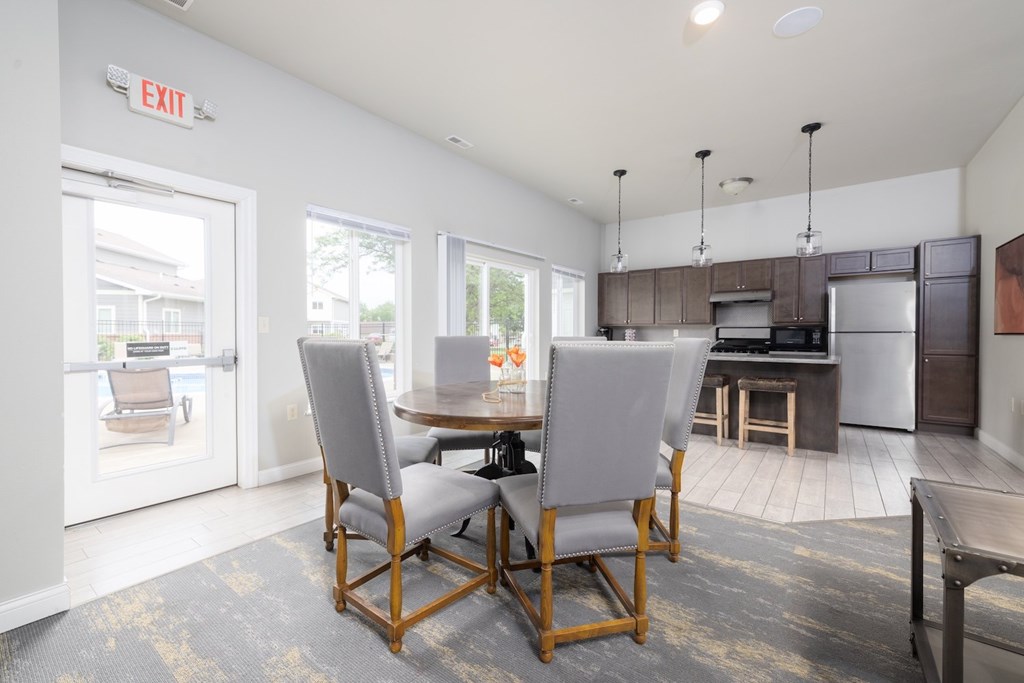 A kitchen with a dining table and chairs in the foreground and an exit sign on the wall.
