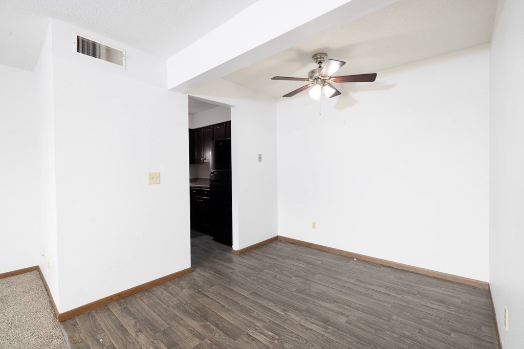 A room with a ceiling fan and wooden flooring.