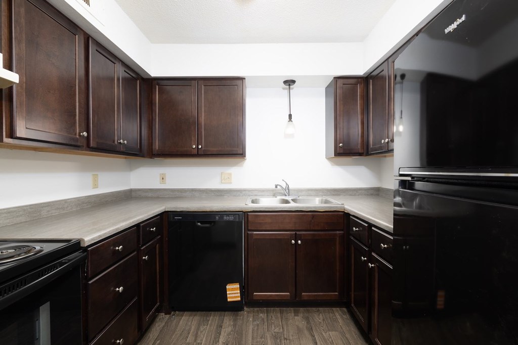A kitchen with dark wood cabinets and black appliances.