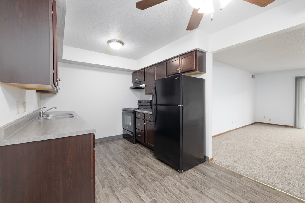 A kitchen with a black fridge and wooden cabinets.