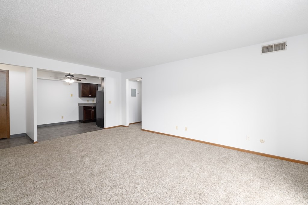 A spacious room with a carpeted floor and a ceiling fan.