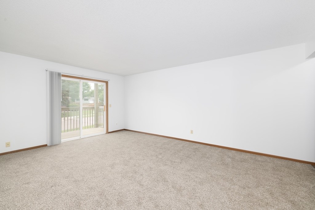 A room with a carpeted floor and a sliding glass door.