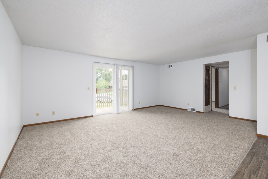 A spacious room with carpeted floor and sliding glass doors.