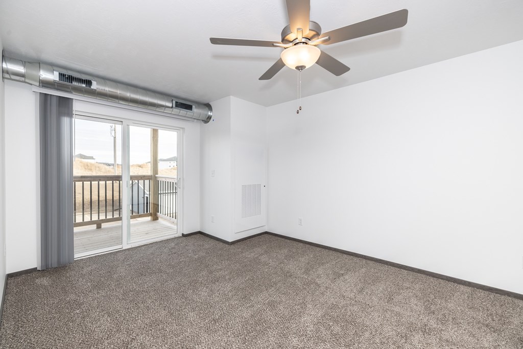 A room with a ceiling fan and carpeted floor.