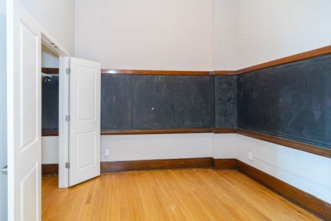 A room with a blackboard on the wall and a wooden floor.