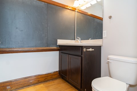 A bathroom with a toilet, sink, and wooden cabinet.